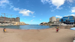 Una platja amb sorra, algunes ombrel·les i un edifici en construcció a la part de darrere.
