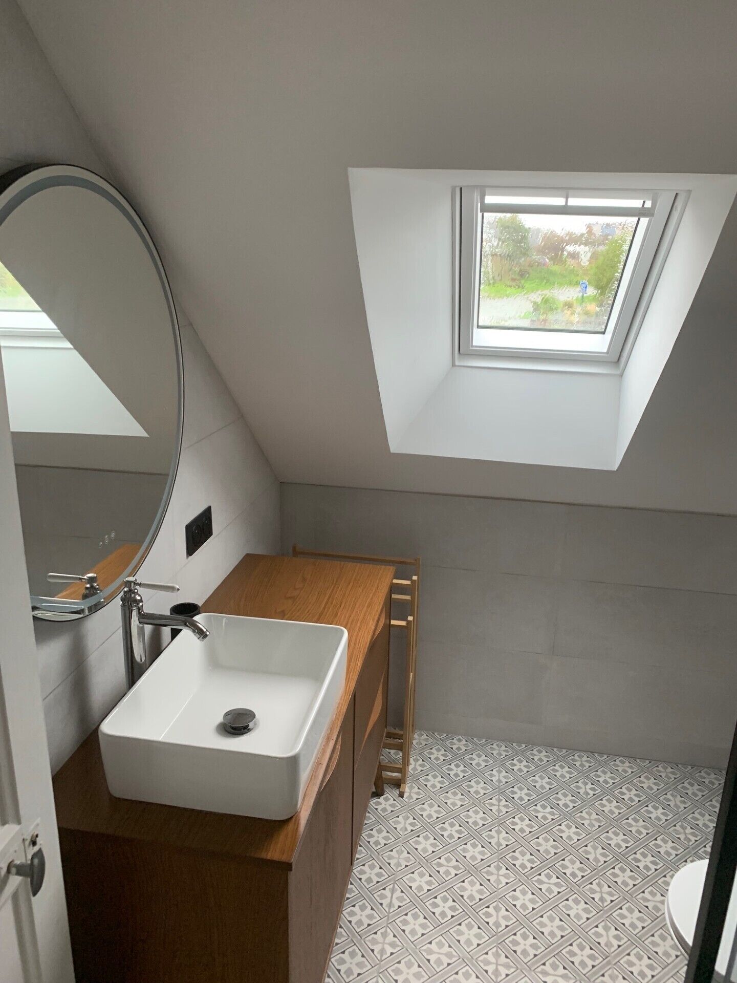 Une petite salle de bain moderne avec un puits de lumière, un lavabo blanc et un meuble-lavabo en bois.