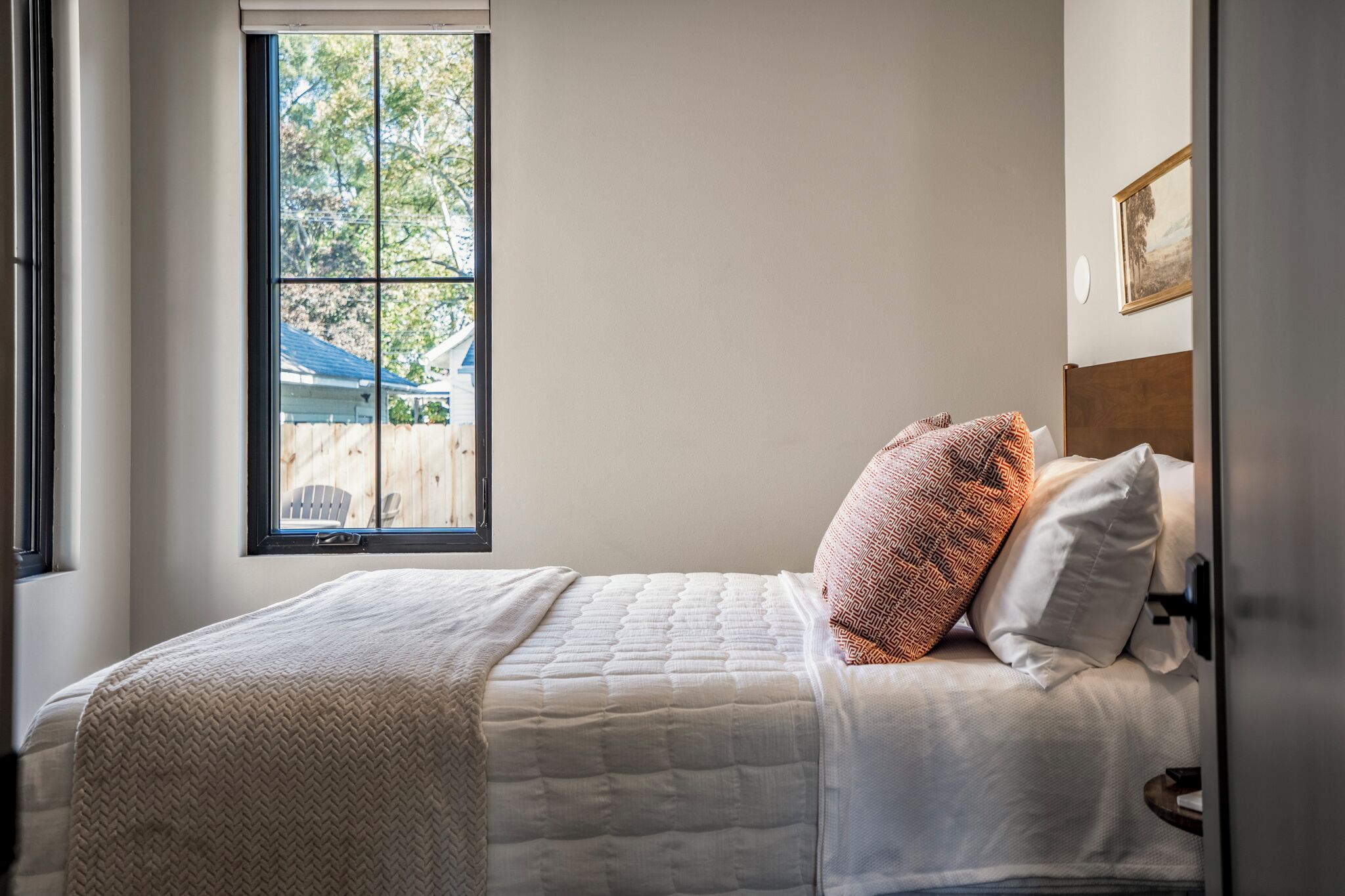 A bedroom with a bed, a window, and a view of the outside.