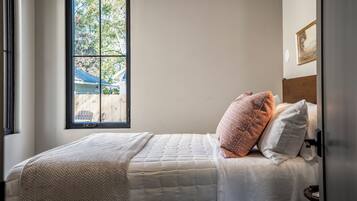 A bedroom with a bed, a window, and a view of the outside.