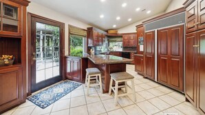 A kitchen with wooden cabinets, a granite countertop, and two stools.