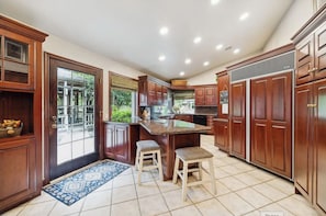 A kitchen with wooden cabinets, a granite countertop, and two stools.