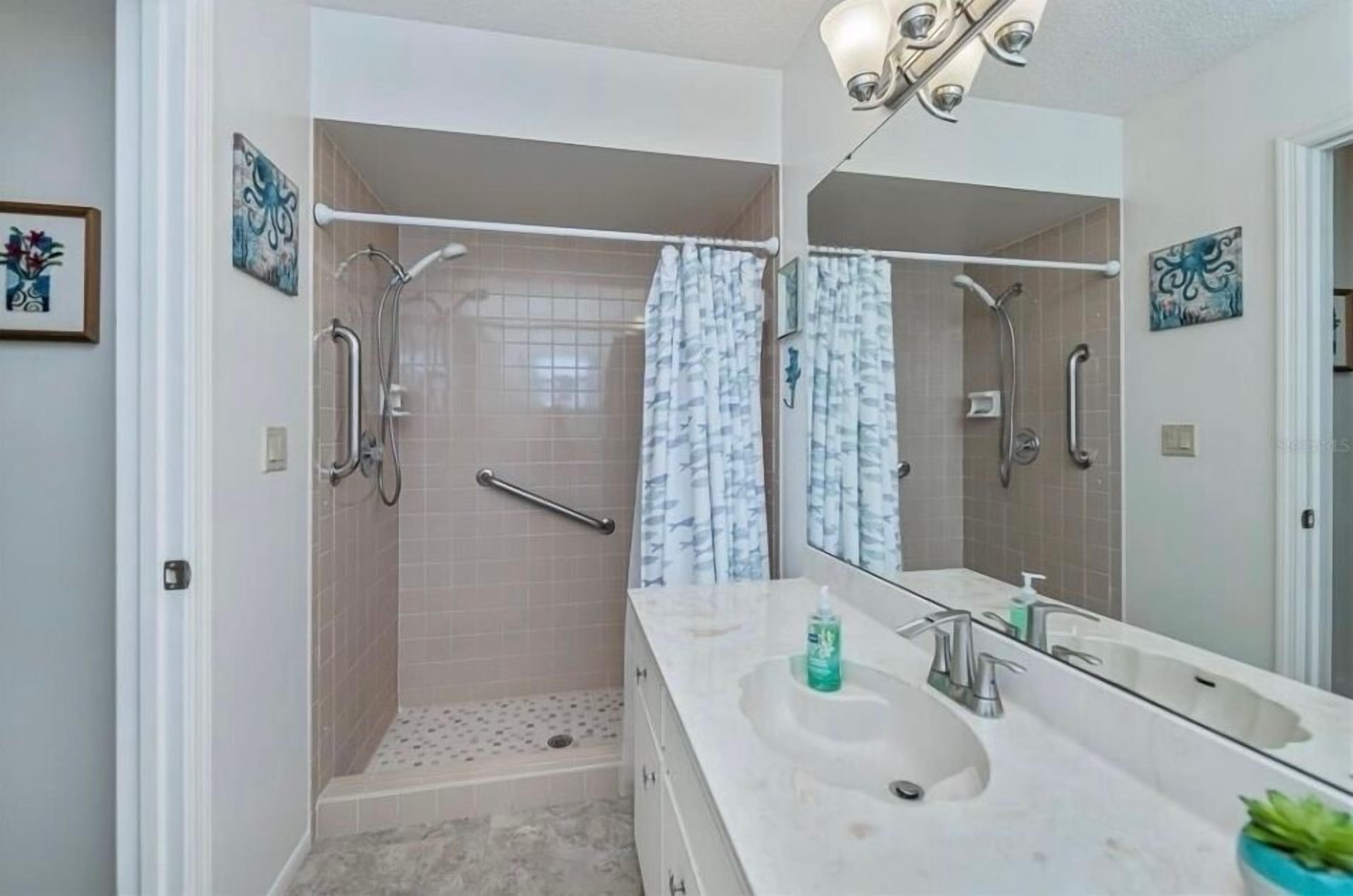 A bathroom with a walk-in shower, a large mirror, and a double sink.