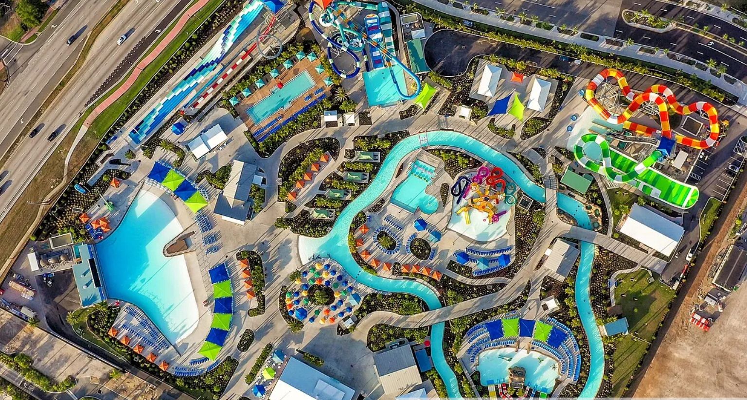An aerial view of a water park with multiple pools, slides, and a winding water ride.