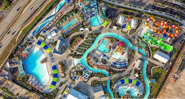 Vue aérienne d’un parc aquatique avec plusieurs piscines, des toboggans et une attraction aquatique sinueuse.