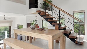 A modern interior with a wooden staircase, a dining table, and potted plants. - Vista Popoyo 3BR Coastal Retreat with Surf & Mangrove Views (Las Salinas)
