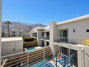 A modern building with a pool, balconies, and a mountain view.