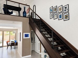 Una escalera con barandilla de madera y balaustradas de metal negro, que conduce a un nivel superior.