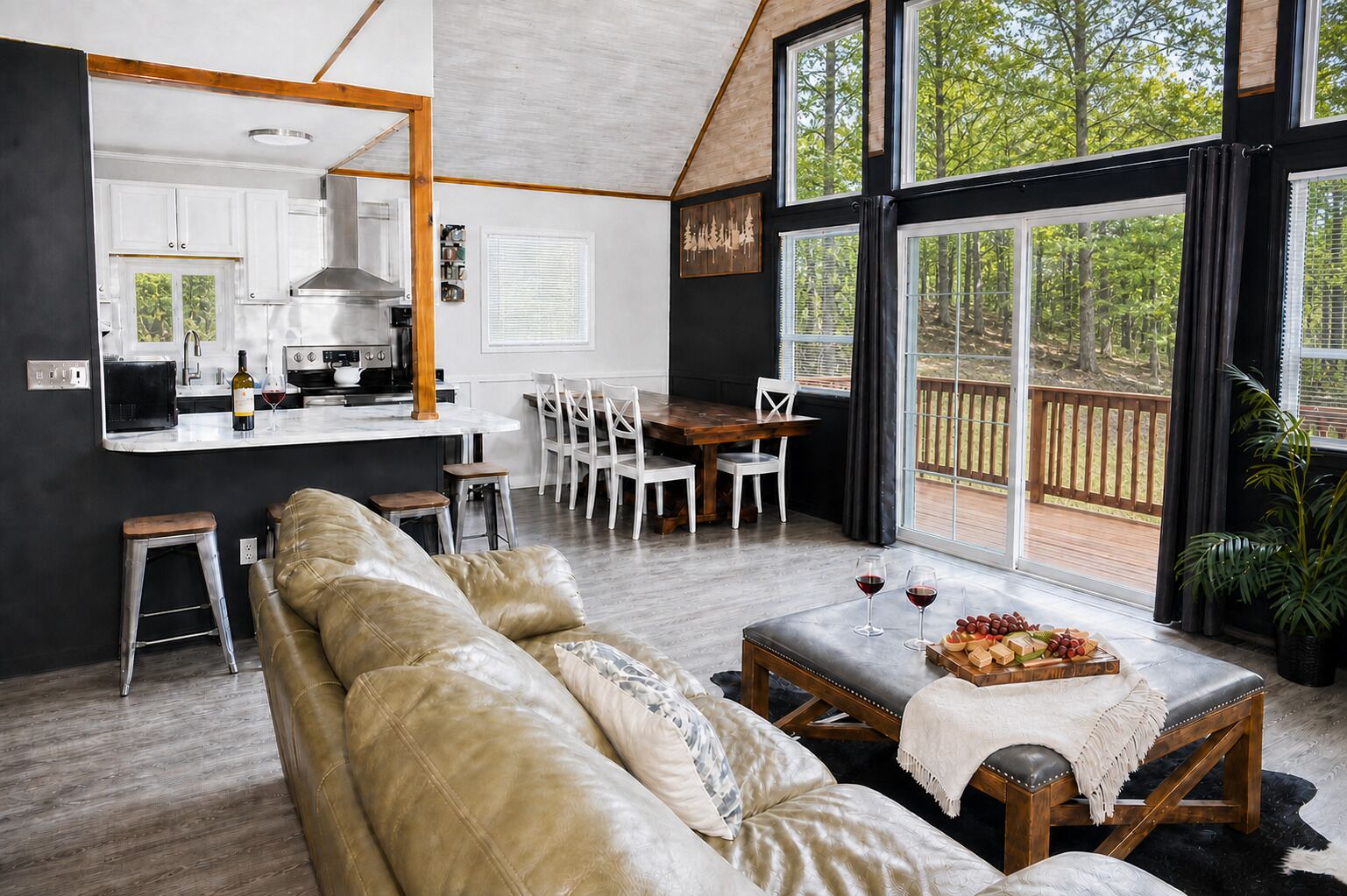 Uma sala de estar espaçosa com sofá de couro, mesa de jantar e cadeiras, cozinha equipada com eletrodomésticos modernos e janelas amplas com vista para o exterior.