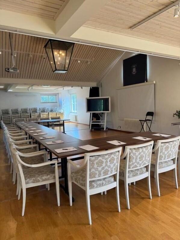 A conference room with a long table, white chairs, a television, and a projector screen.