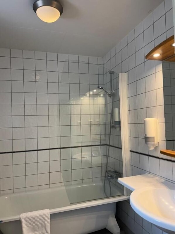 Une salle de bain moderne avec une douche à parois de verre, un lavabo blanc et un miroir avec un cadre en bois.