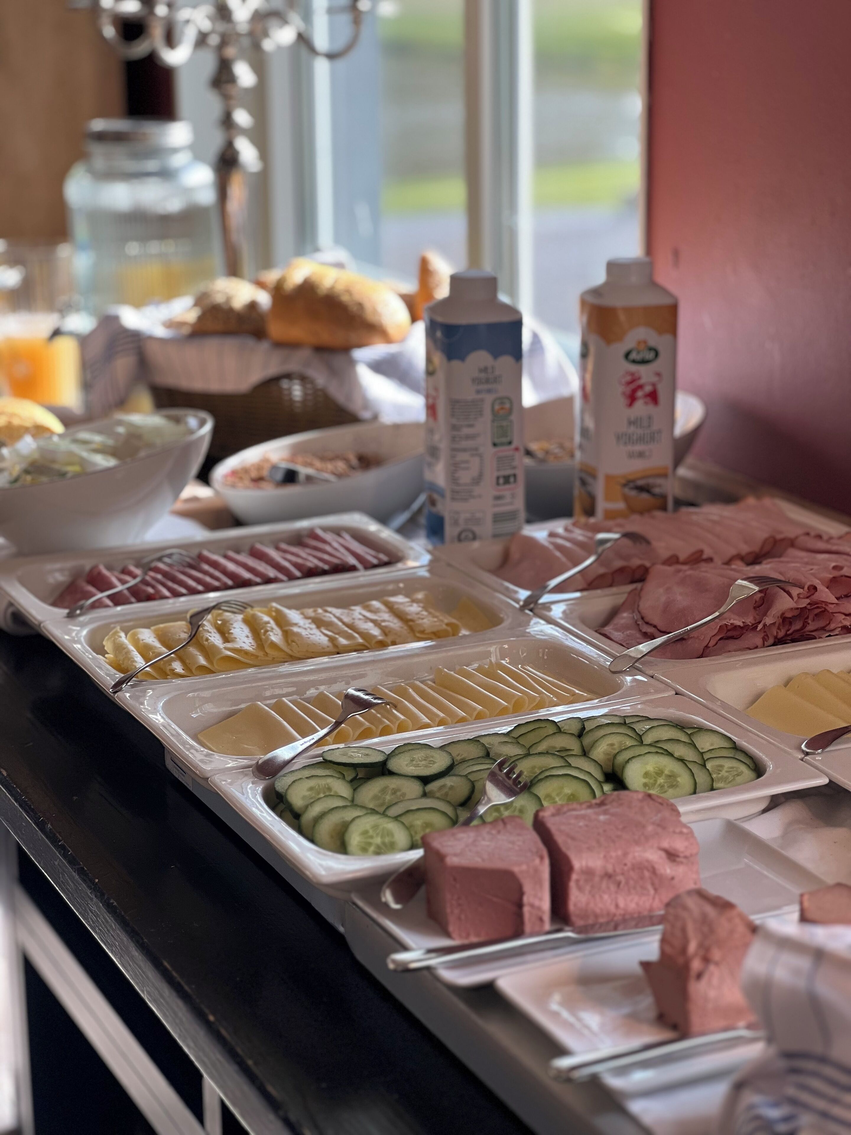Un buffet proposant une variété d’aliments, notamment des concombres en tranches, du fromage et de la charcuterie.