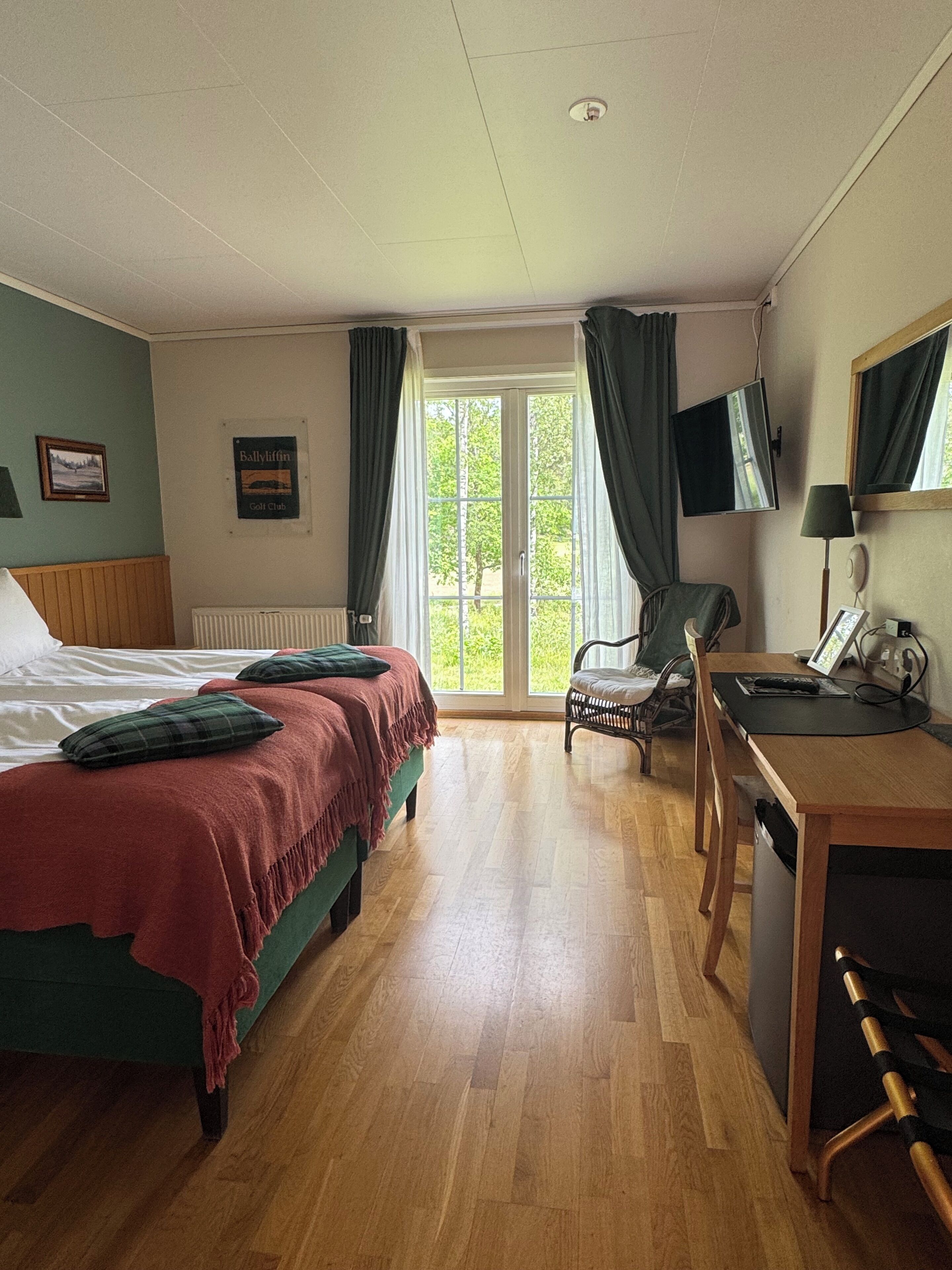 A hotel room with a bed, a desk, a chair, a television, and a window with curtains.