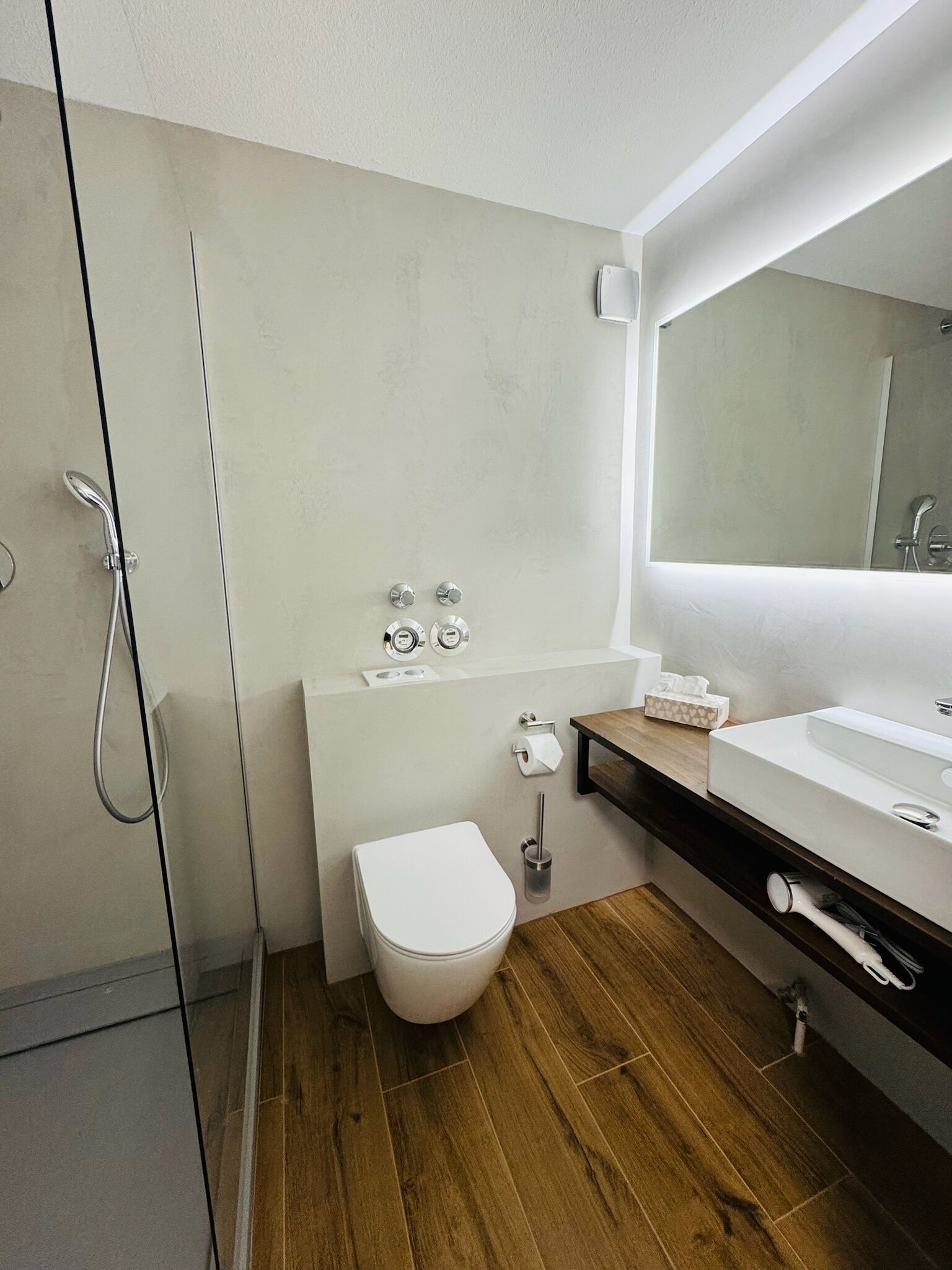 A modern bathroom with a shower, toilet, and sink.