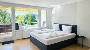 Camera moderna con un letto grande, un comodino e vista all'aperto attraverso ampie finestre.