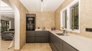 A modern kitchen with a built-in oven, a sink, and a window. - Villa Tranquila (Denia)
