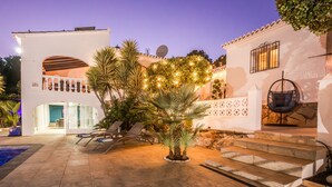 A courtyard with a pool, lounge chairs, and a palm tree. - Villa Tranquila (Denia)