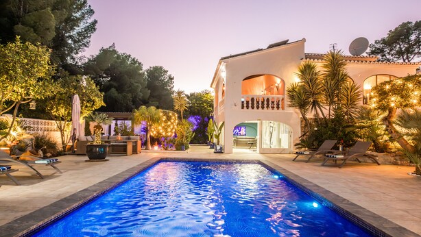 A swimming pool with lounge chairs and a building with a balcony. - Villa Tranquila (Denia)