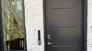 Eine moderne Tür mit Zahlenschloss und einem Fenster zur Linken.