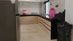 A modern kitchen with a white brick backsplash, a large window, and a black countertop. - Pawna Ns4 villa (Mawal)