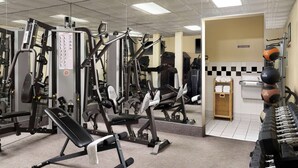 Ett gym med olika träningsmaskiner, en bänk och hantlar.