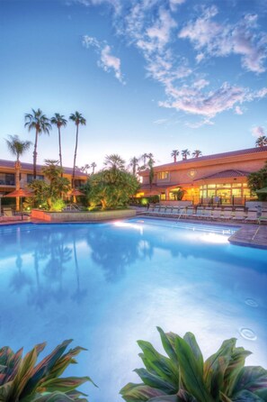 Et resort med swimmingpool, palmer og en bygning med flere balkoner.