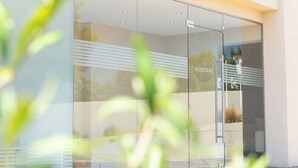 A modern building with a glass facade, a visible sign reading "ARSCAPE," and a reflection of trees and sky. - AIRSCAPE HOTEL FREE SHUTTLE ATH AIRPORT (Spata-Artemida)