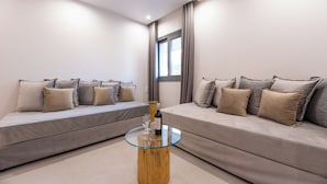 A modern living room with two grey sofas, a glass coffee table, and a bottle of wine. - AIRSCAPE HOTEL FREE SHUTTLE ATH AIRPORT (Spata-Artemida)