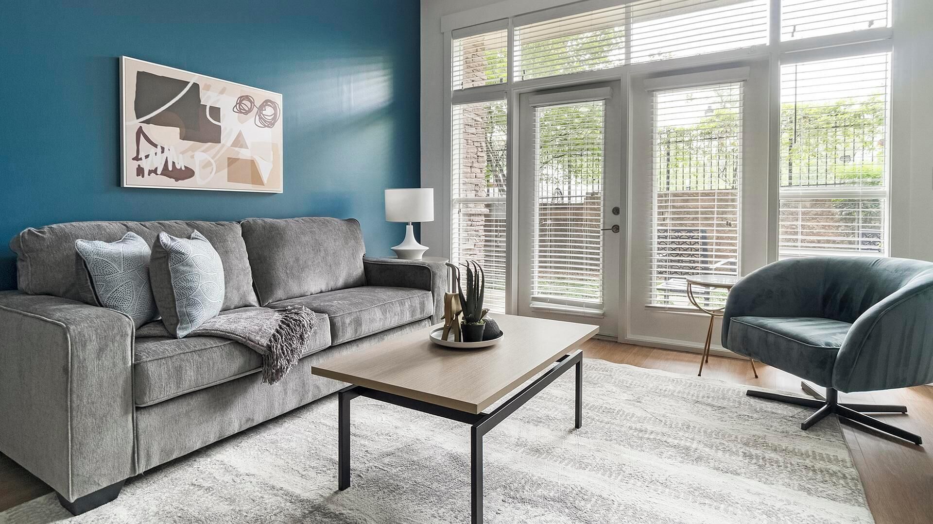 A living room with a grey sofa, a coffee table, and a blue armchair.