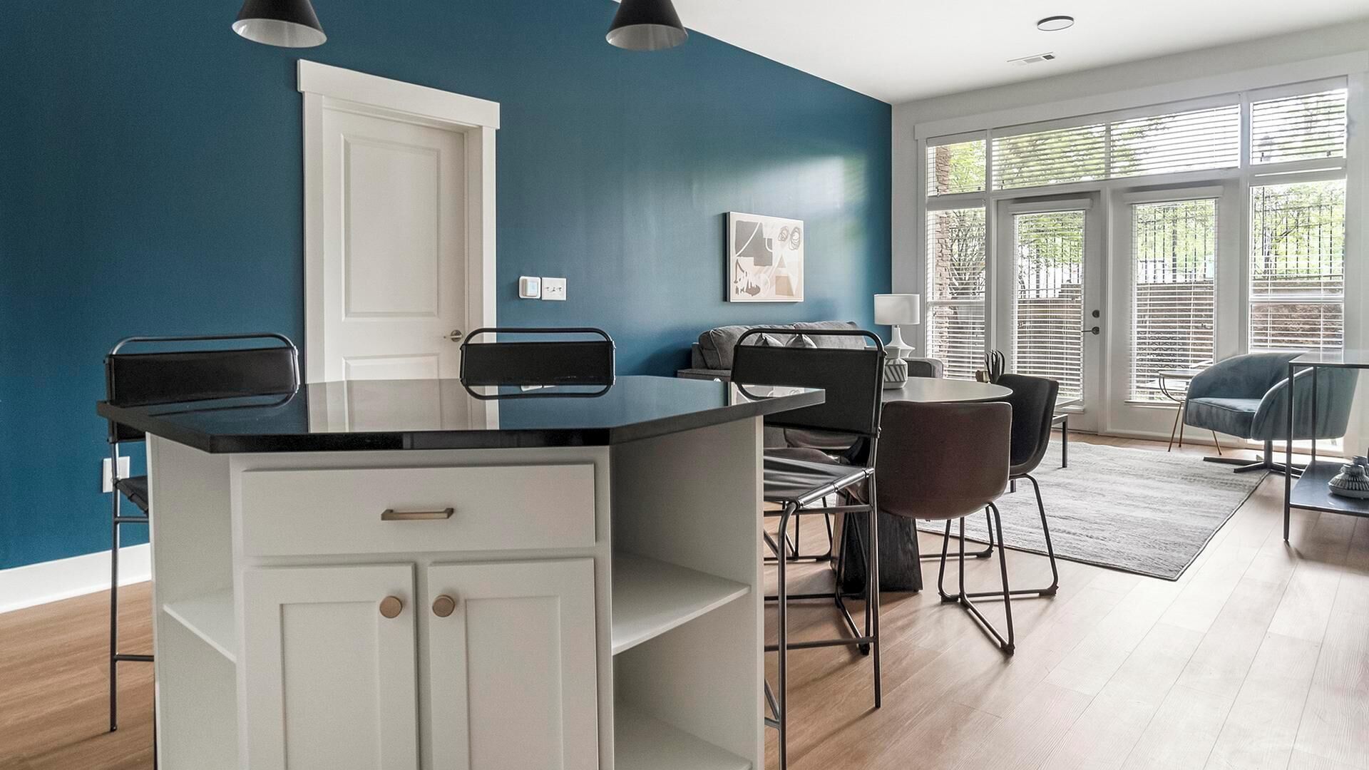 A modern kitchen with a central island, white cabinetry, and a blue accent wall.