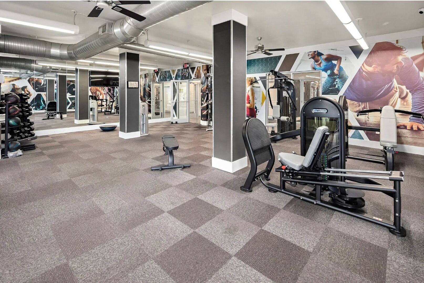 Ein Fitnessstudio mit unterschiedlichen Trainingsgeräten, Spiegelwänden und einem Schachbrettboden.