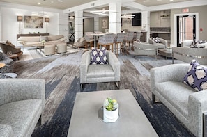 A spacious lobby with multiple seating areas, a coffee table with a plant, and a visible exit sign.