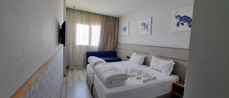 Una habitación de hotel con una cama grande, una silla azul y una ventana con cortinas.