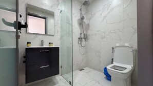 A modern bathroom with a glass shower enclosure, a toilet, and a vanity with drawers. - Seashell (Oualidia)