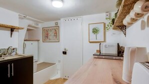 Eine moderne Küche mit weißen Schränken, einer Holz Arbeitsplatte und einem weißen Kühlschrank.