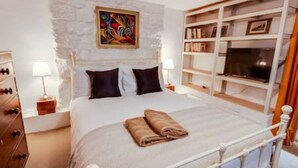 Ein Schlafzimmer mit einem Bett, einem Nachttisch, einer Kommode, einem Bücherregal und einem Bild an der Wand.