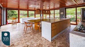 Cocina amplia con una isla grande, techo de madera y ventanas que dan a vistas de vegetación.