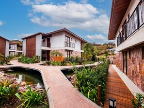 A residential area with modern houses, a small bridge, and a landscaped garden with a pond.