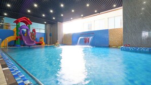 Una piscina coperta con uno scivolo acquatico, un'area giochi e una cascata.