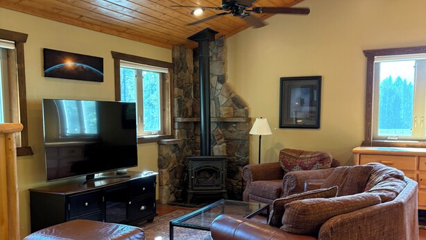 Una sala de estar acogedora con chimenea de piedra, sofá de cuero y televisor de pantalla plana.