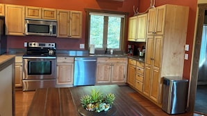 Una cocina moderna con armarios de madera, electrodomésticos de acero inoxidable y un ventanal que proporciona luz natural.