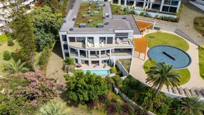 Un hotel moderno de varios pisos con jardín en la azotea, piscina y césped bien cuidado.