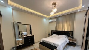 Une chambre à coucher comprenant un lit, des tables de chevet, une commode, un miroir et un luminaire au plafond.