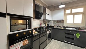 Une cuisine moderne équipée d’un four encastré, d’un four à micro-ondes et d’un lave-linge.