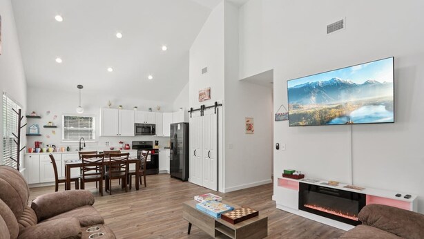 Una sala de estar moderna con chimenea, televisor de pantalla plana y comedor con muebles de madera.