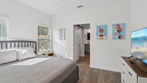 Un dormitorio con cama, ventilador de techo y televisión.