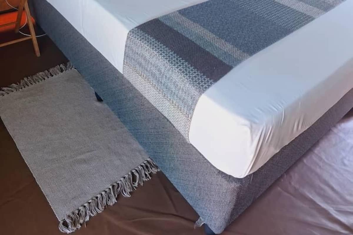 Ein Zeltraum mit Bett, Kissen, Decke und einem kleinen Tisch.