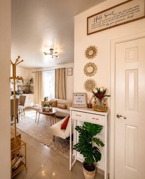 A modern living room with a sofa, coffee table, and a decorative mirror. There is a white door with a sign above it and a plant on the floor. - Casa Campos: Perfect Blend of Comfort and Elegance! (San Miguel)