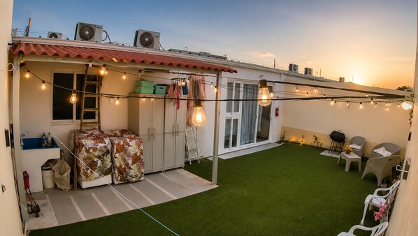 A rooftop patio with artificial lighting, a small seating area, and a green artificial turf. - Casa Campos: Perfect Blend of Comfort and Elegance! (San Miguel)