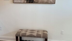 Een lijstwerk met een afbeelding van een jak op de muur, een bank met een gestreept kussen, en een wandlamp.